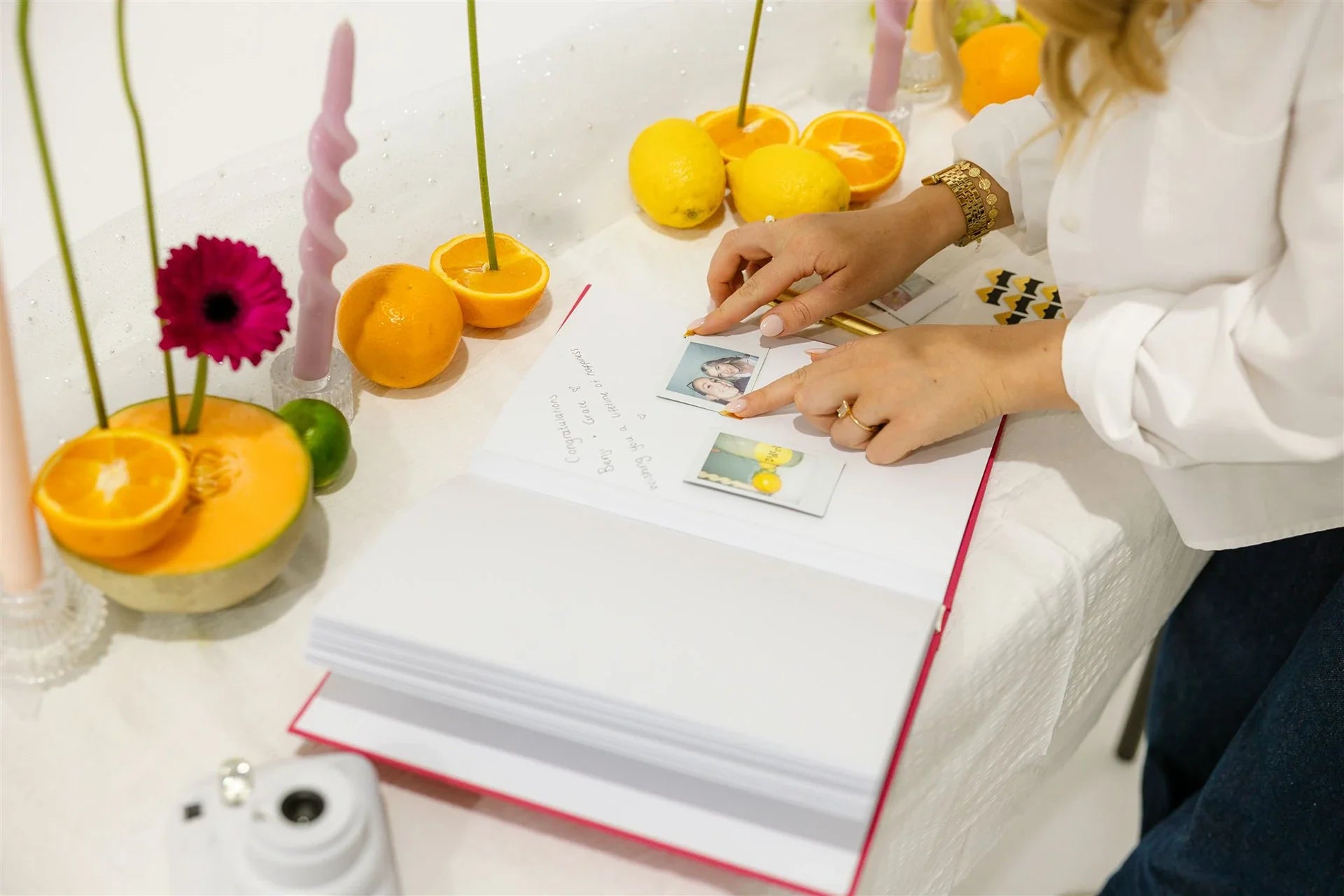 Personalised wedding polaroid book with polaroid photos scattered to the side, along with a gold pen